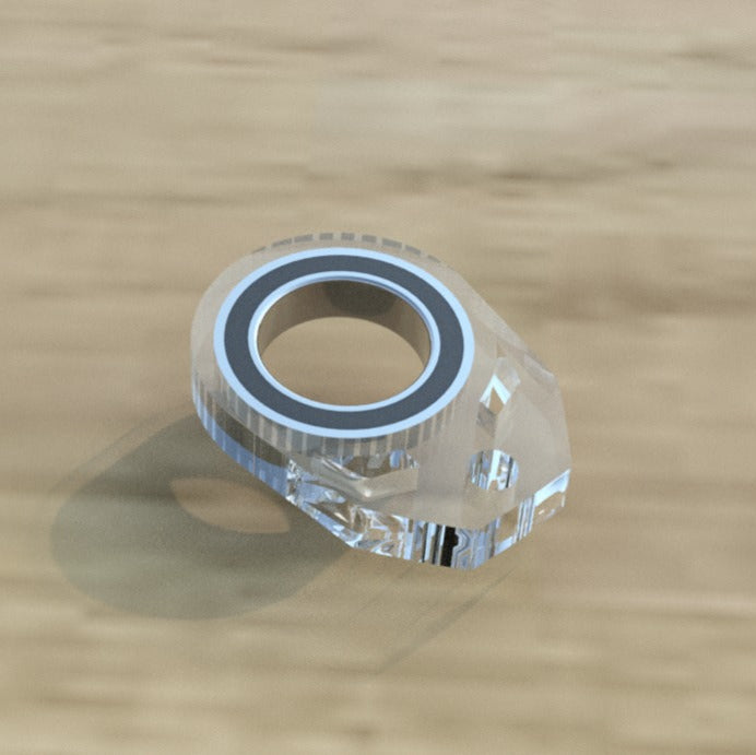 Clear plastic component with a metallic ring on a wooden surface bearing keychain spinner